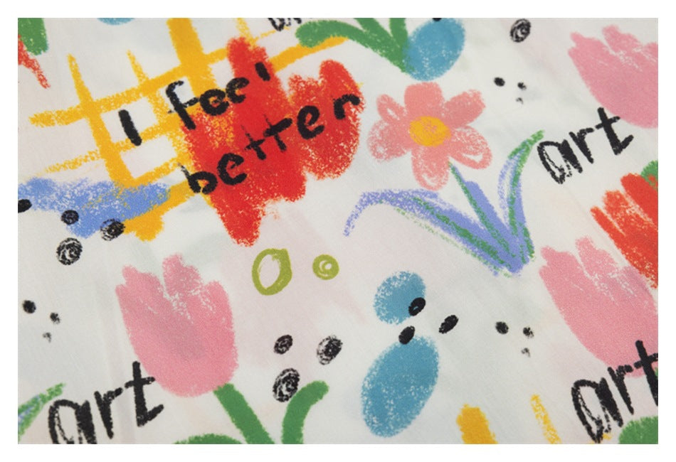Close-up of colorful abstract flowers, shapes, and black English lettering printed on white fabric.