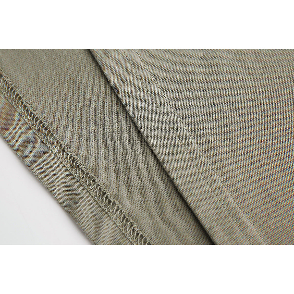 Close-up of khaki T-shirt fabric showing an overlocked seam and parallel stitching.