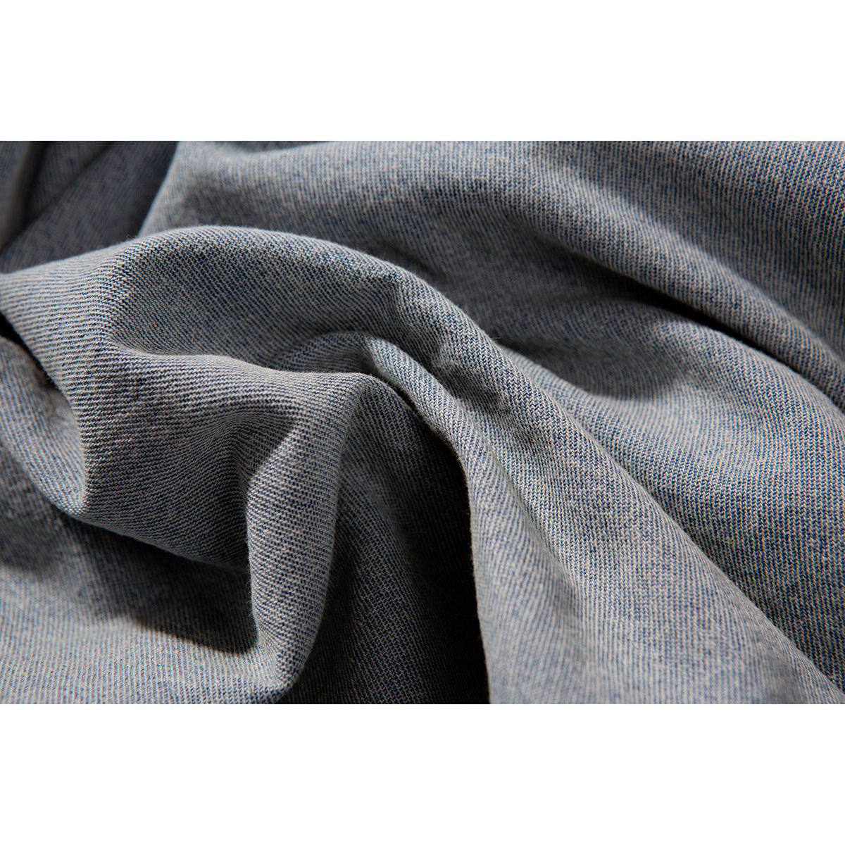 Macro view of light blue denim fabric gathered into soft folds.