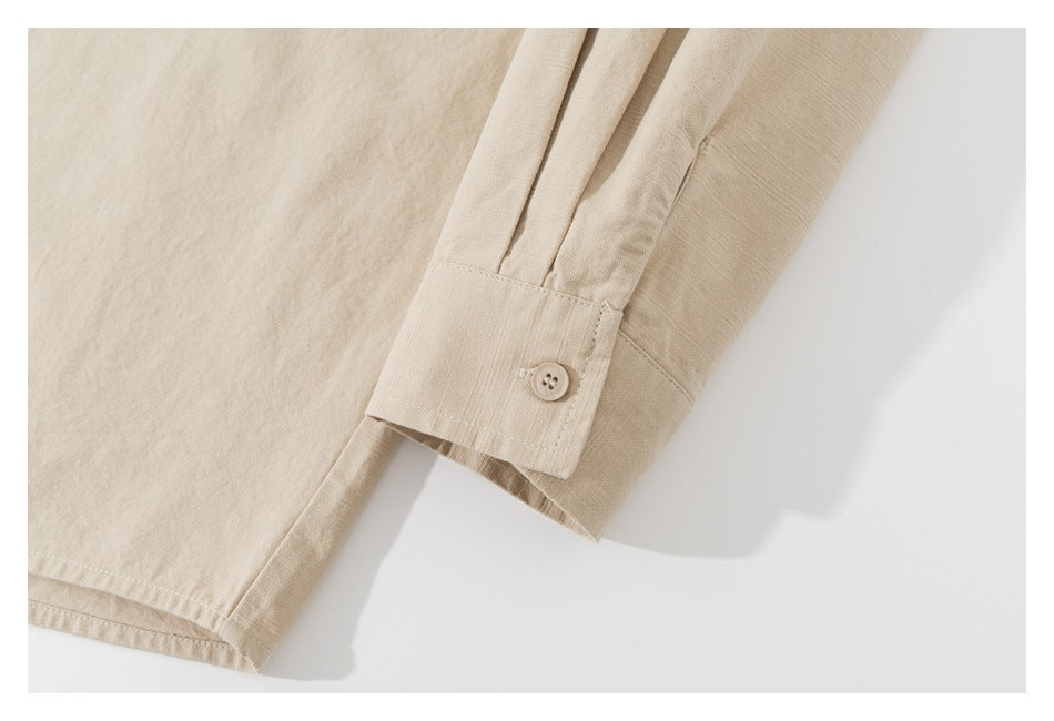 Close-up of a beige shirt sleeve cuff with a button and stitched hem.