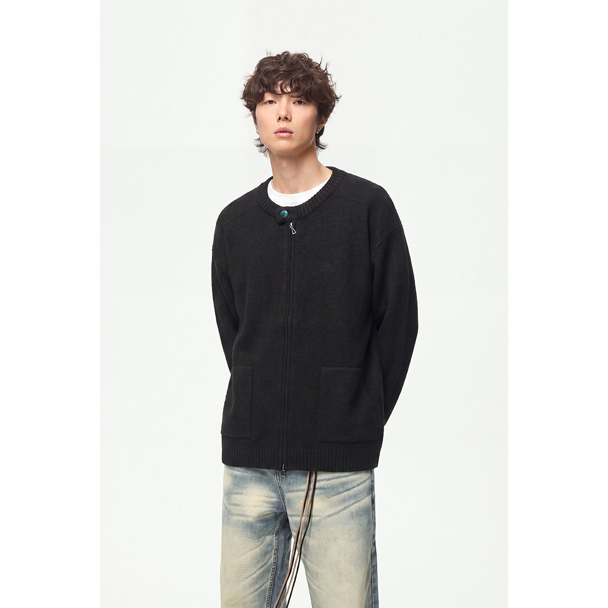 Model wearing a black knit cardigan with a front zipper, ribbed crew neck and hem, and two patch pockets.