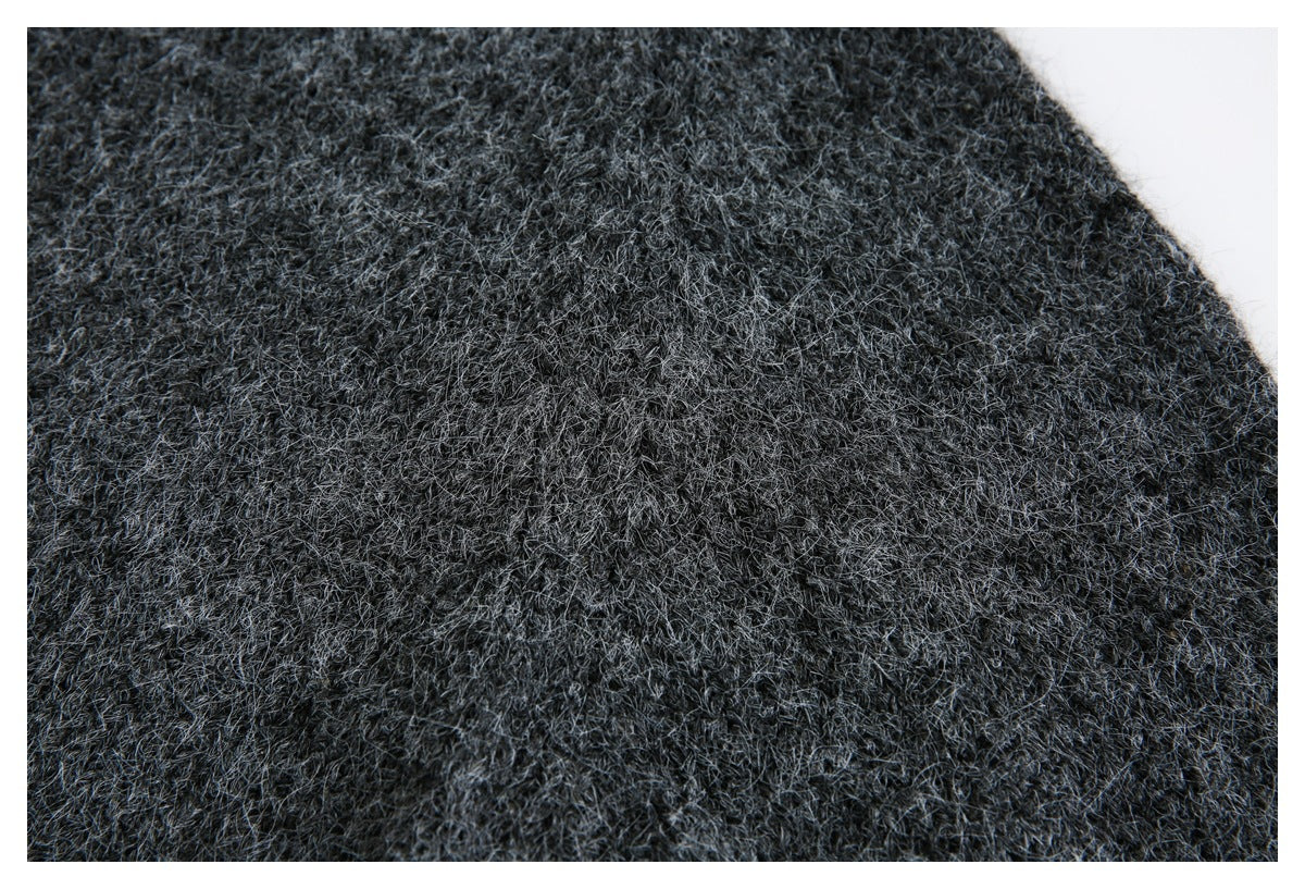 Close-up of dense, fuzzy charcoal gray knit texture with a curved fabric edge.