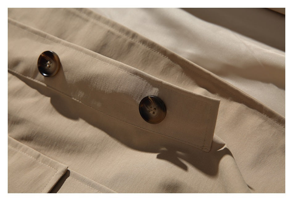 Close-up of two dark brown buttons on the beige coat's front placket.