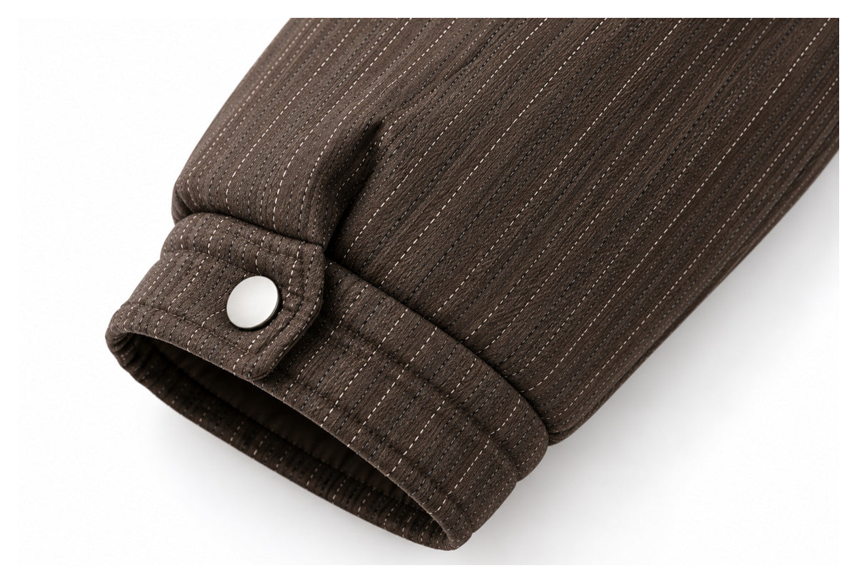 Close-up of a dark brown garment sleeve cuff with fine dotted stripes and a silver snap button.