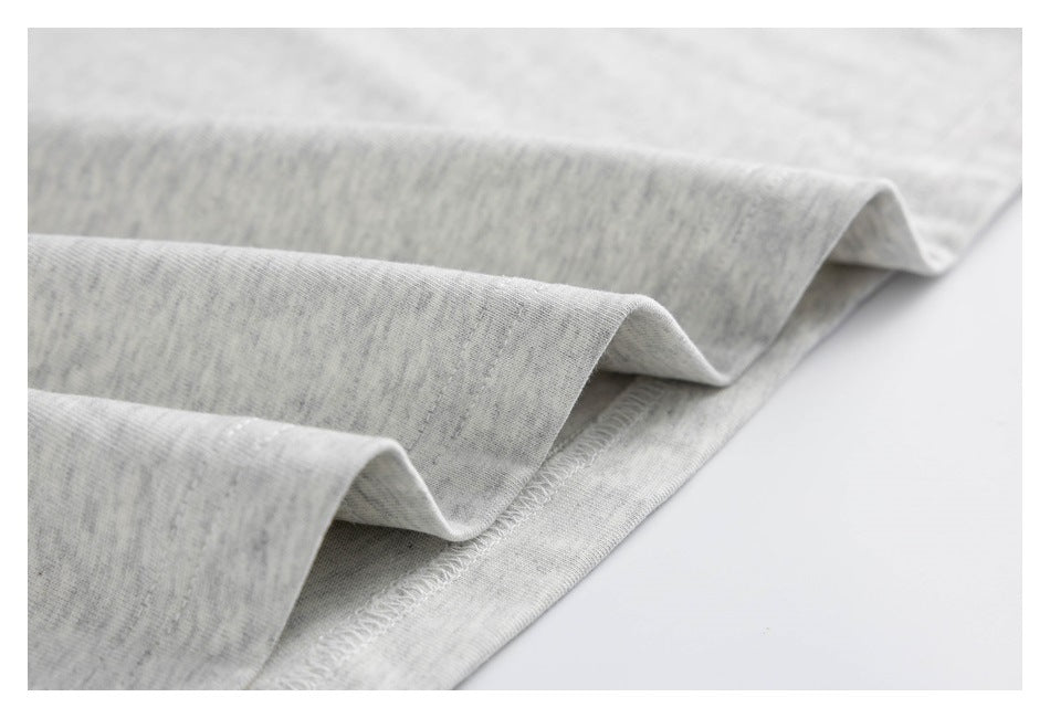 Close-up of a folded hem with overlocked stitching on light gray heather fabric.