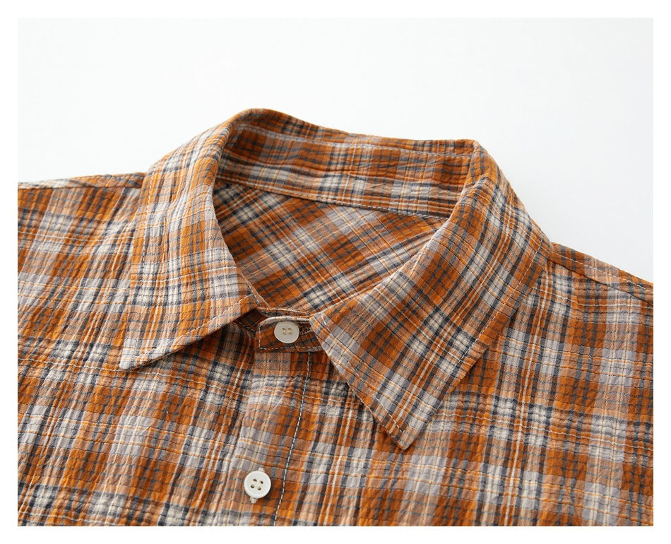 Close-up of an orange, gray, and cream plaid shirt collar and button placket.