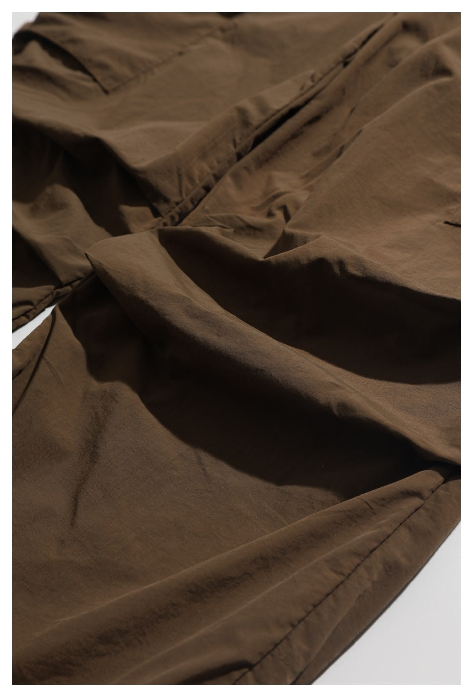 Close-up of brown shorts fabric, seams, and folded panels.