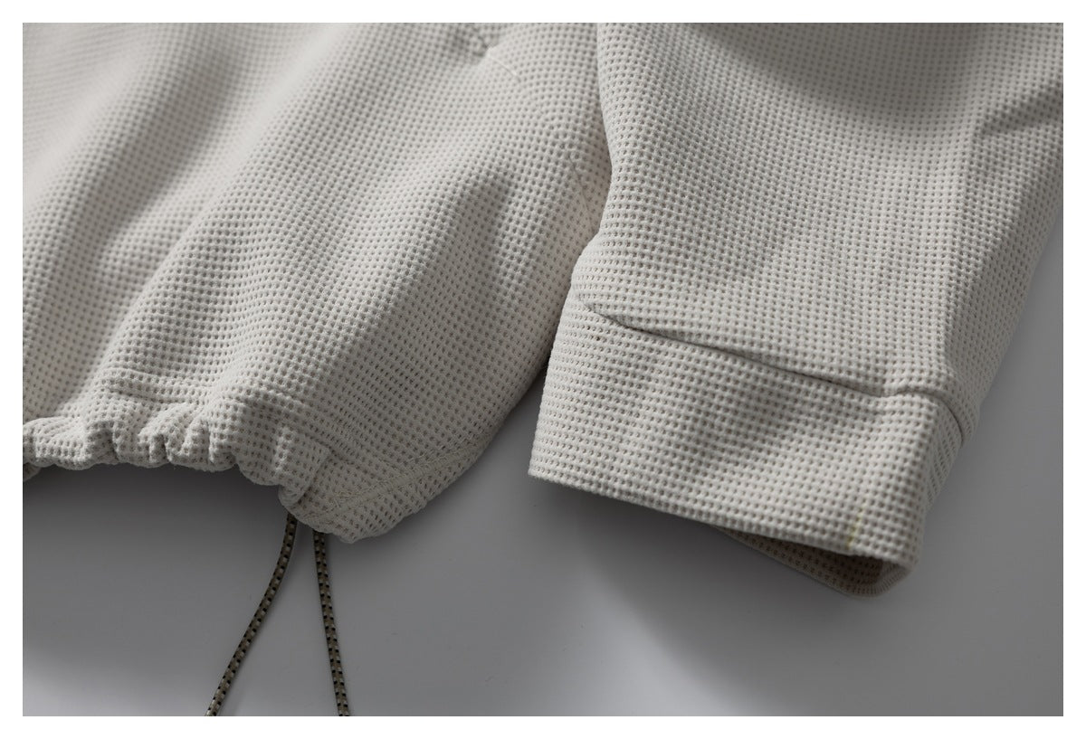 Close-up showing the jacket's gathered drawcord hem beside a wide sleeve cuff.