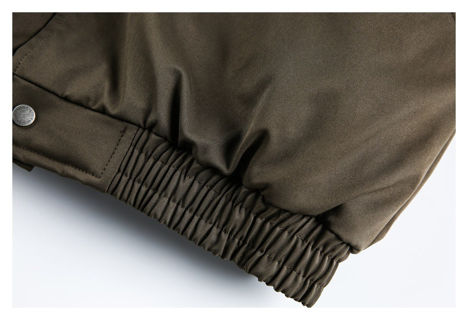 Close-up of an olive-brown garment's gathered elastic waistband and a silver snap button.