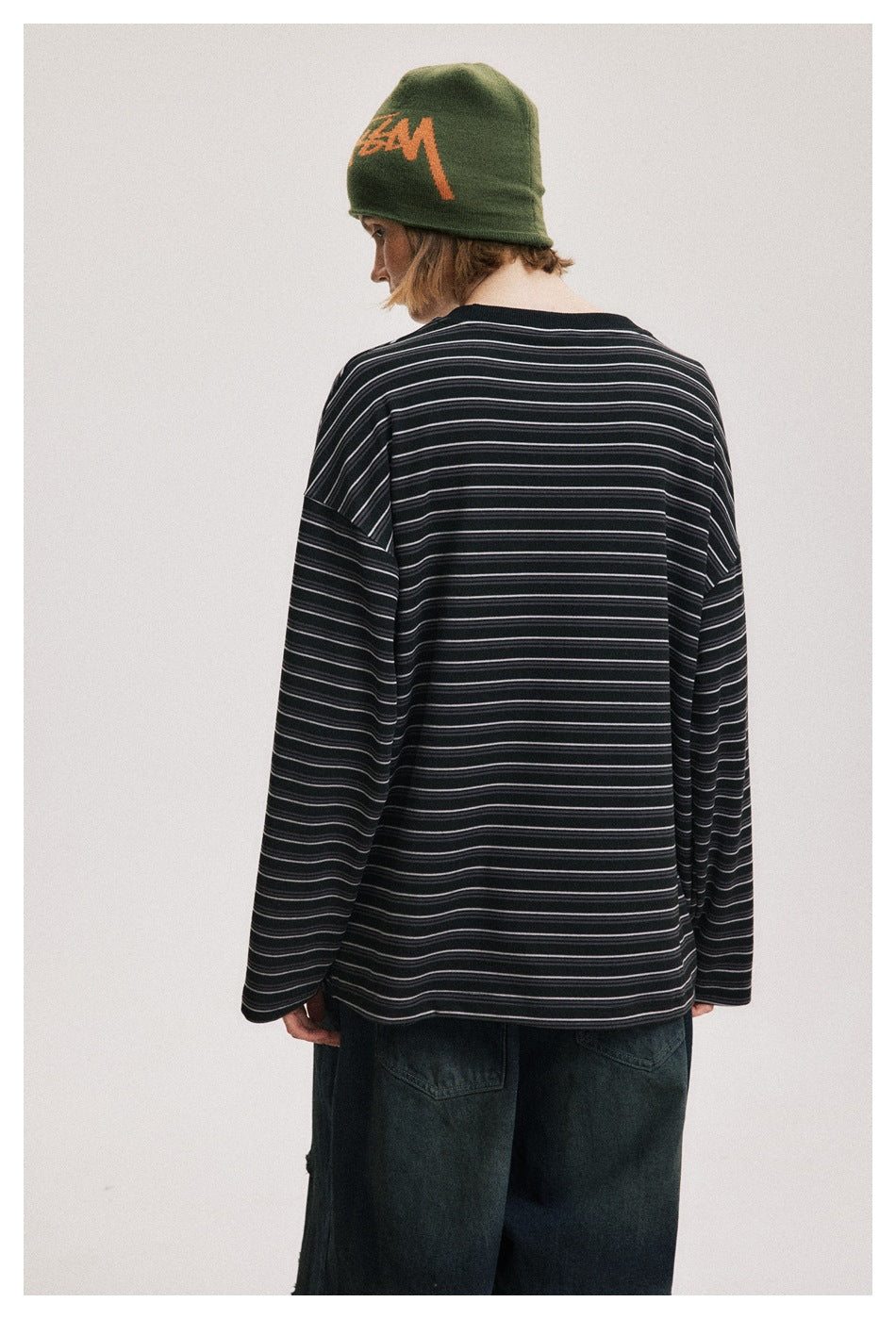 Back view of a person wearing a loose black long-sleeve shirt with thin light stripes.