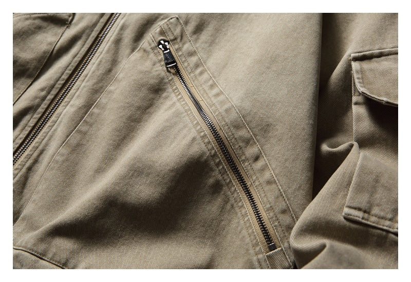 Close-up of a taupe jacket's diagonal zip pocket, stitching and sleeve flap pocket.