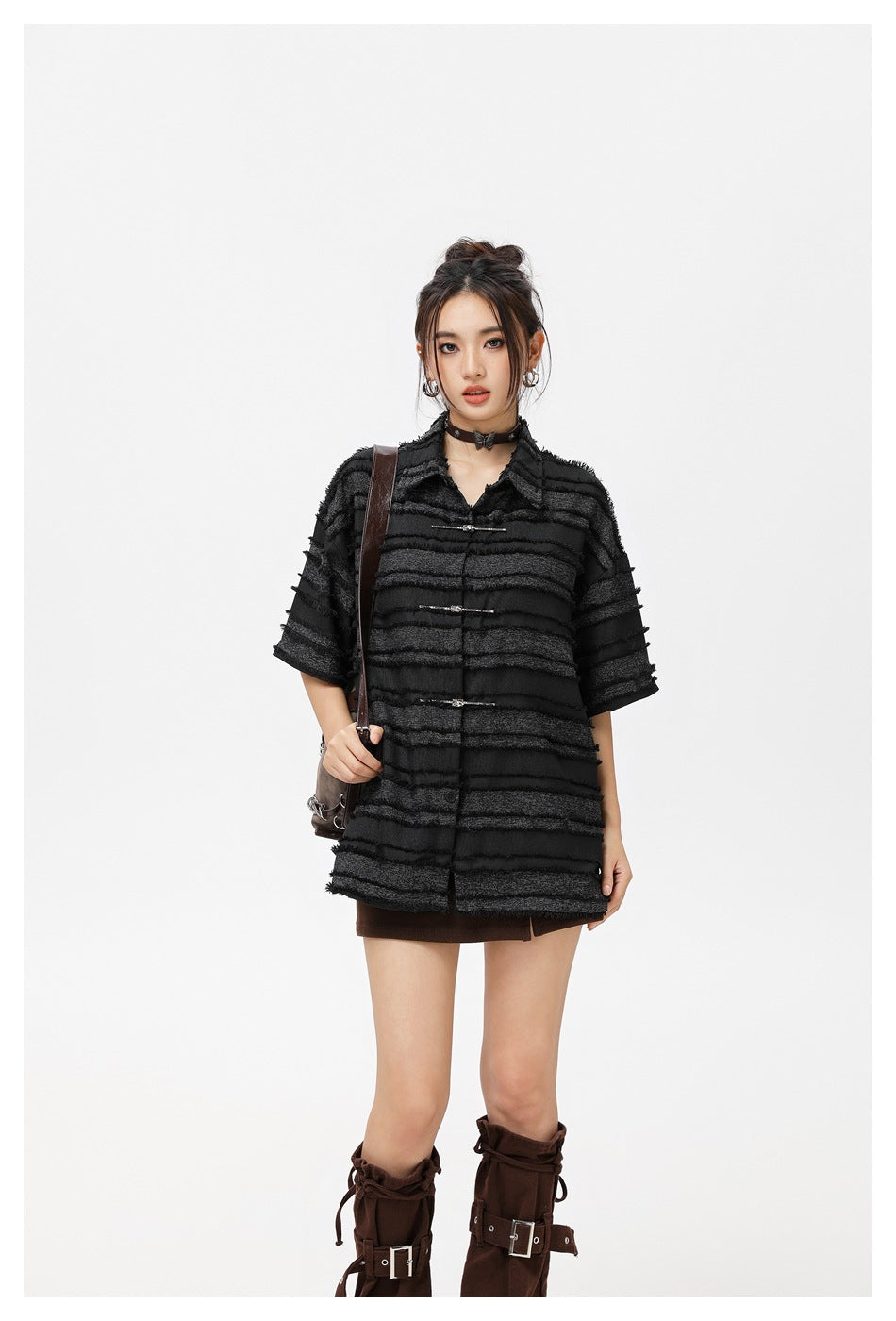 Model wearing an oversized black short-sleeve shirt with horizontal textured stripes and metal frog closures.