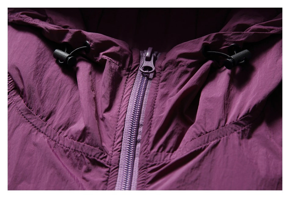 Close-up of a plum jacket's front zipper, hood drawcord toggles, and stitched panels.