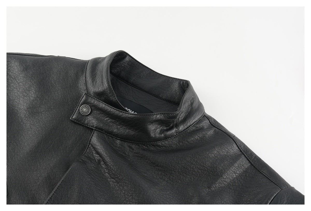 Close-up of a black jacket's stand collar and snap tab against a light background.