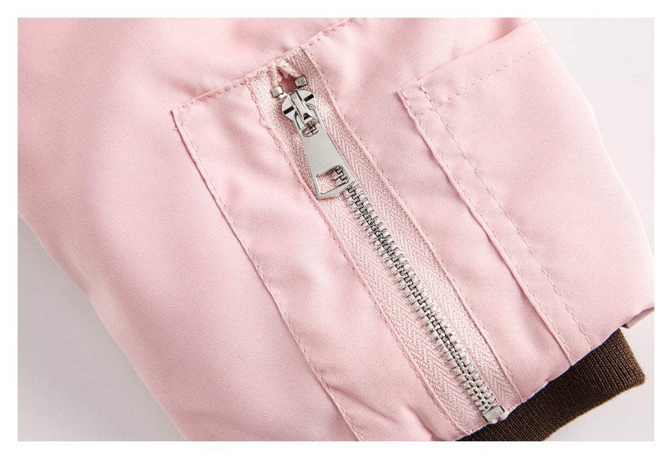 Close-up of a silver zipper and dark brown ribbed cuff on a pale pink jacket.