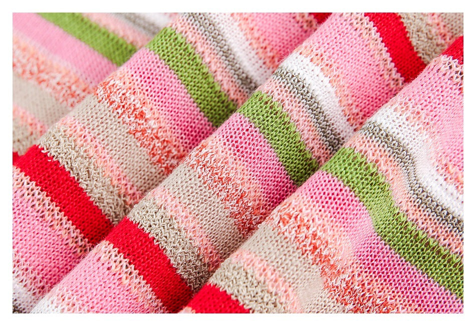 Macro view of the open knit texture and multicolored stripes in pink, red, green, white, and beige.