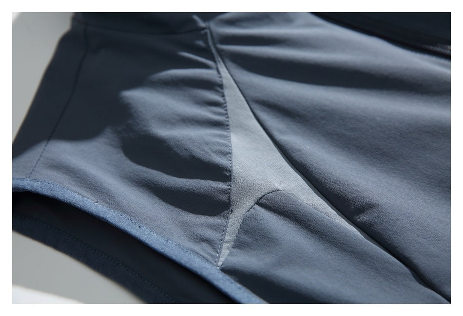 Close-up of slate blue-gray garment fabric with curved panel seams and a finished edge.