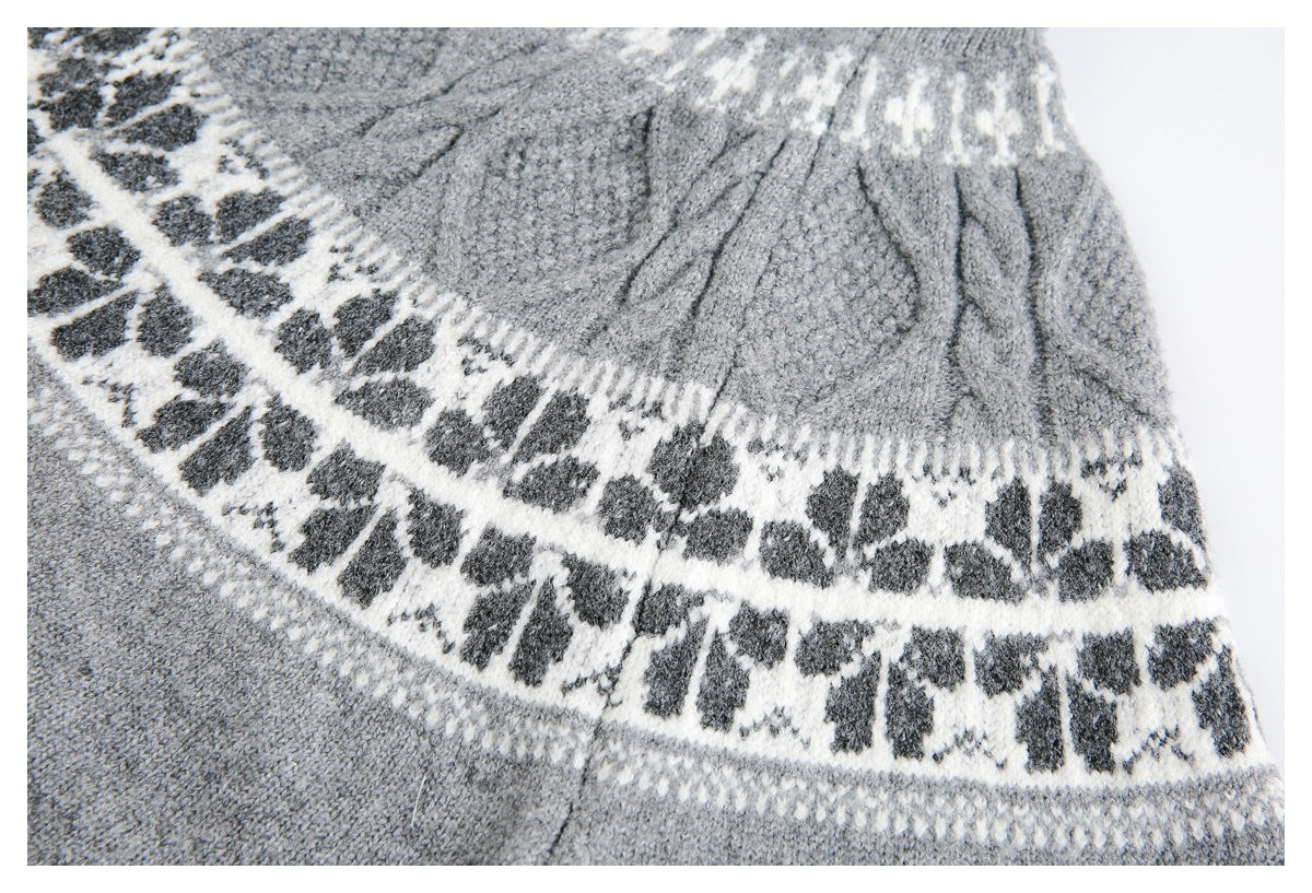 Close-up of a gray sweater's textured knit yoke and layered white bands with dark geometric motifs.