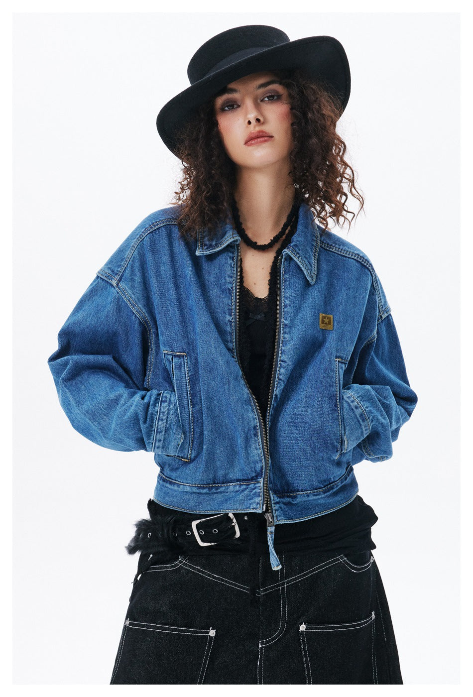 Close front view of a model wearing a blue denim zip jacket with a pointed collar and two front pockets.