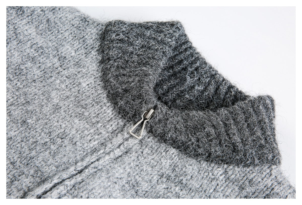 Close-up of a gray marled knit garment with a dark folded edge and a small metal hook clasp.