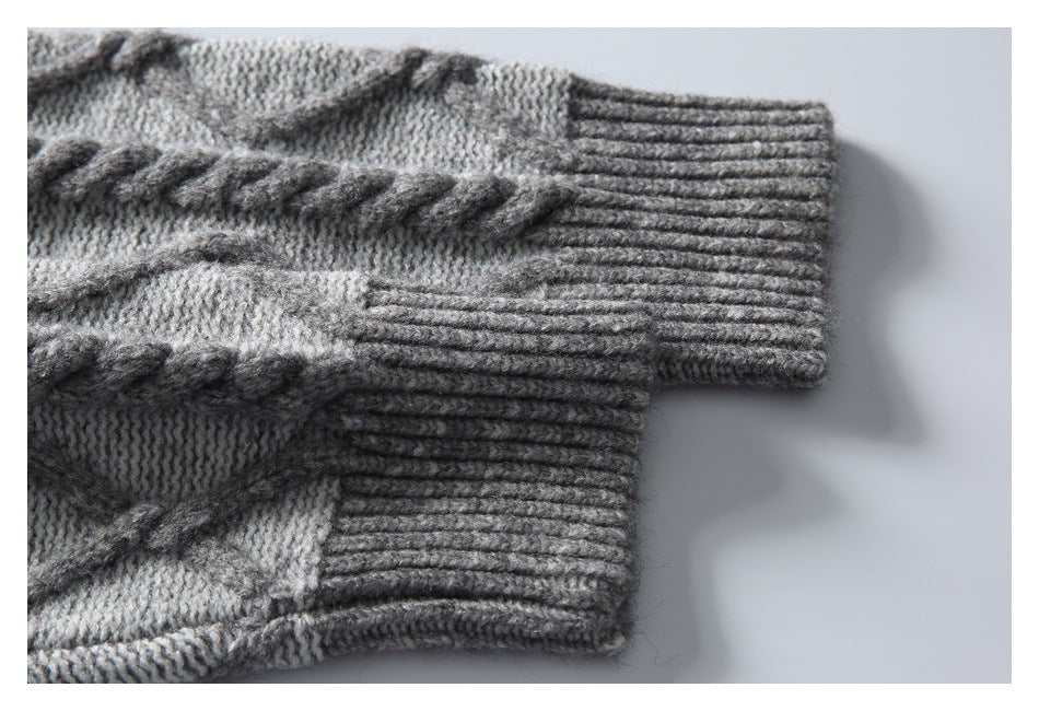 Close-up of a gray sweater sleeve with a wide ribbed cuff and raised cable-knit detail.
