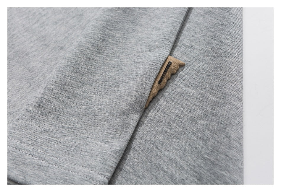 Close-up of a heather-gray T-shirt with a small tan fabric label at a seam.