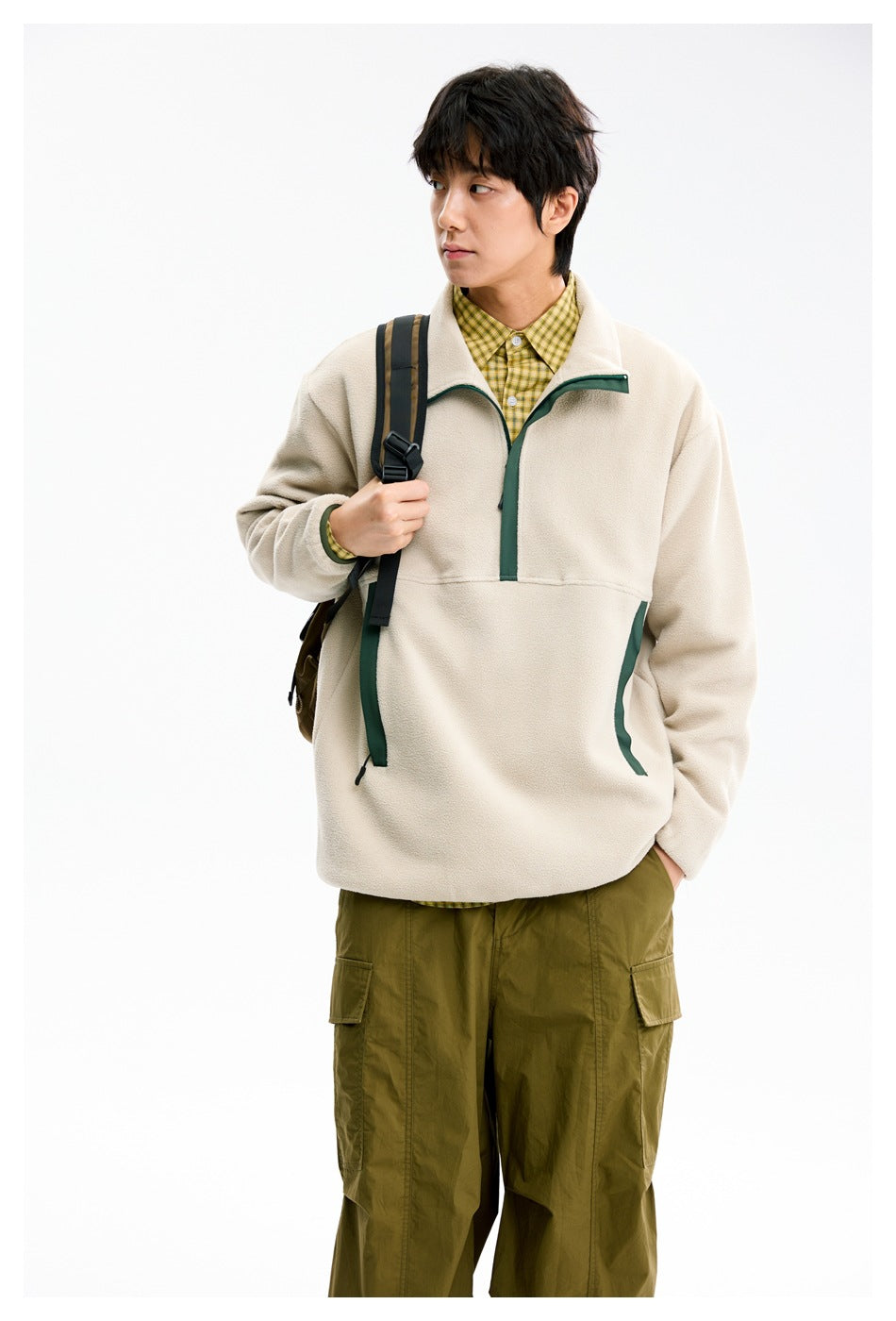 Closer front view of a model wearing a cream pullover with dark green trim and an olive cargo outfit.