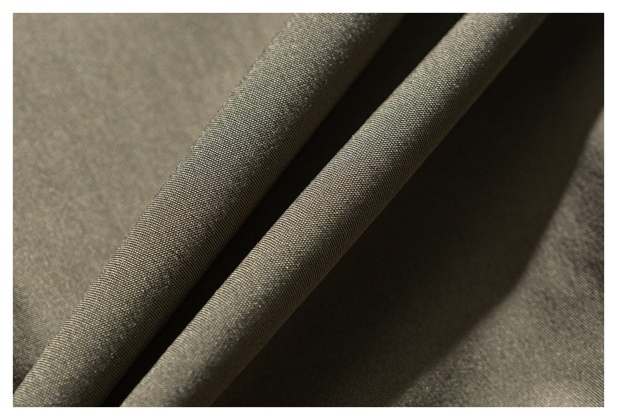 Close-up of dark olive-brown woven fabric folded into soft ridges.