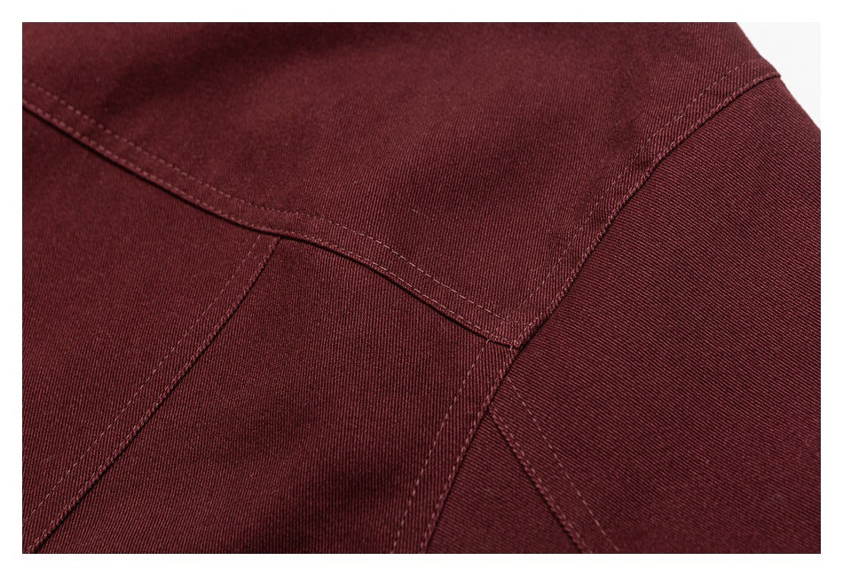 Close-up of intersecting stitched seams on burgundy fabric.