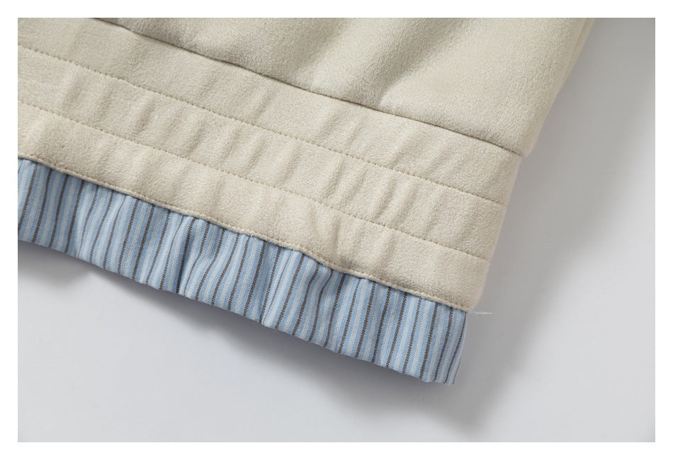 Close-up of the cream garment's stitched hem and blue striped lining.
