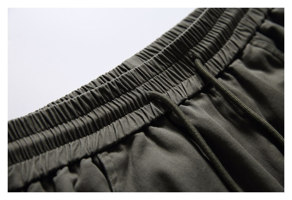 Close-up of the gathered elastic waistband and drawstring on dark olive-gray pants.