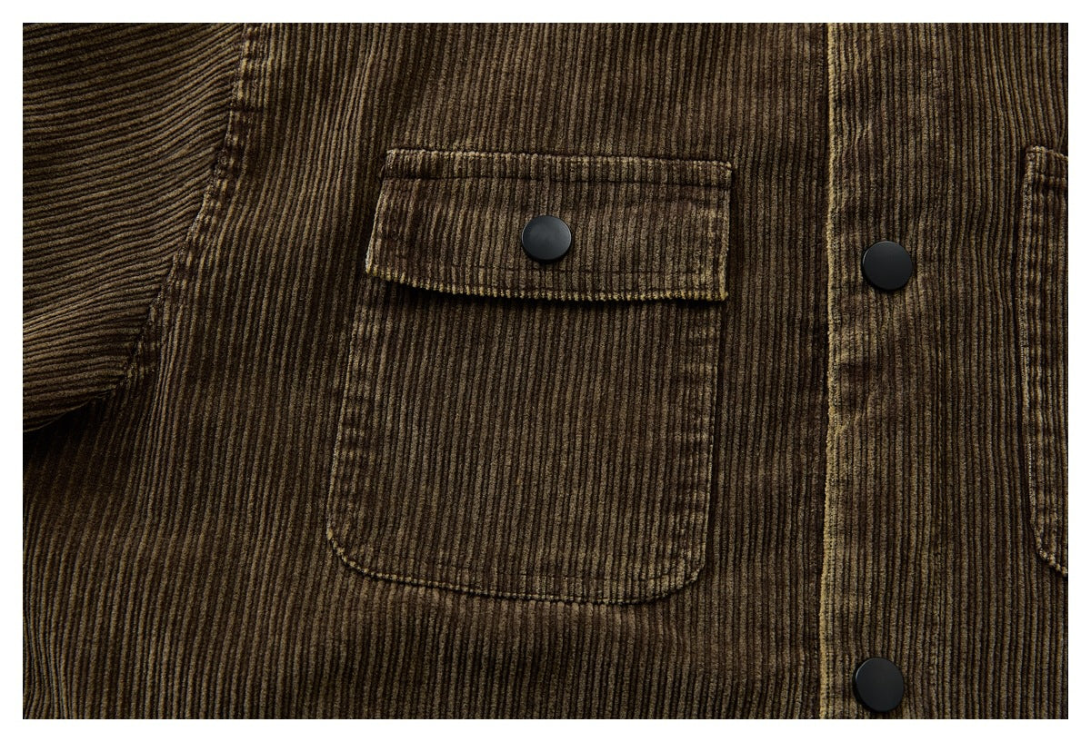 Close-up of a brown corduroy jacket with a buttoned chest pocket and black snaps.