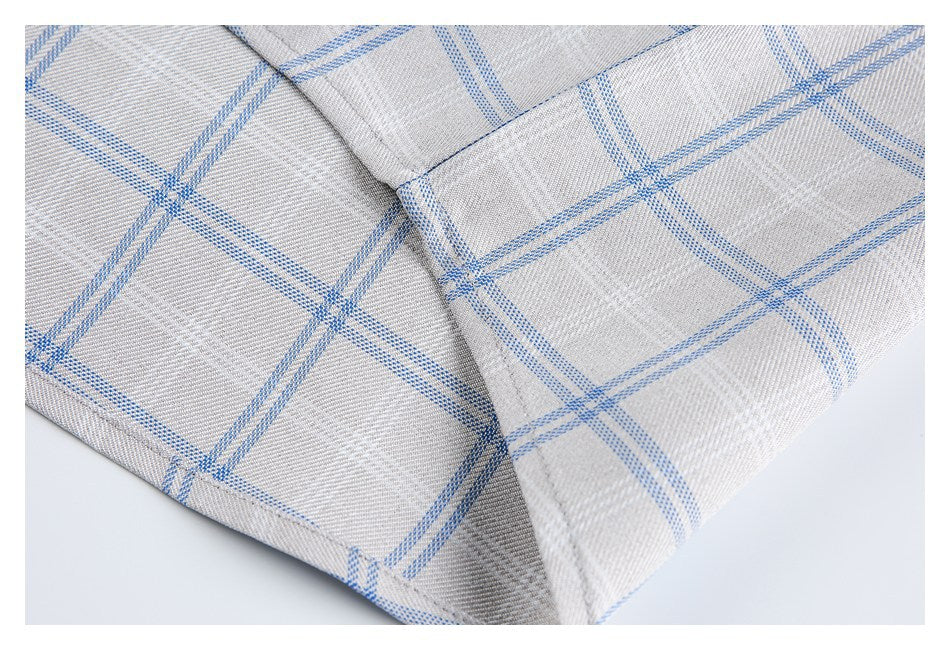 Close-up of a folded, stitched edge on light gray shirt fabric with a blue windowpane check.