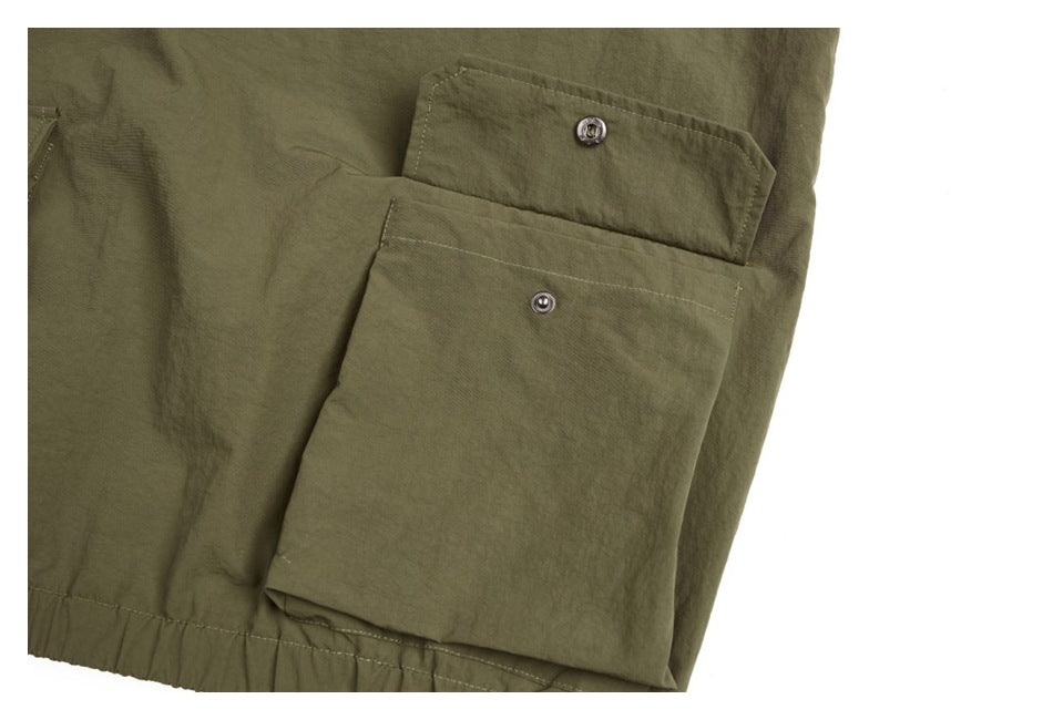 Close-up of a large olive jacket pocket with a snap-fastened flap and gathered hem.