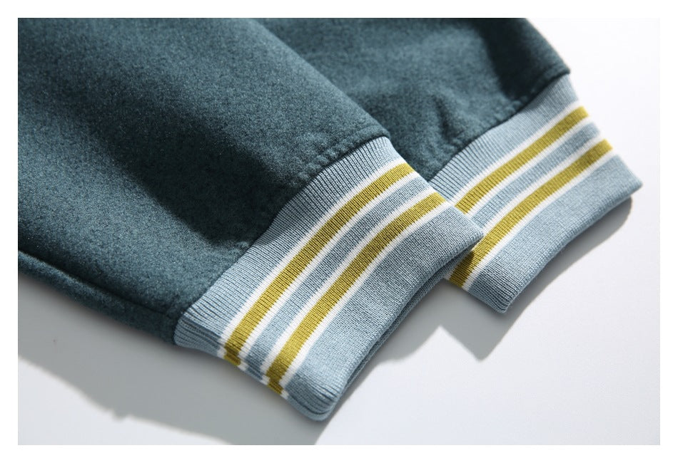 Close-up of dark teal garment edges with light blue ribbed trim striped in mustard and white.