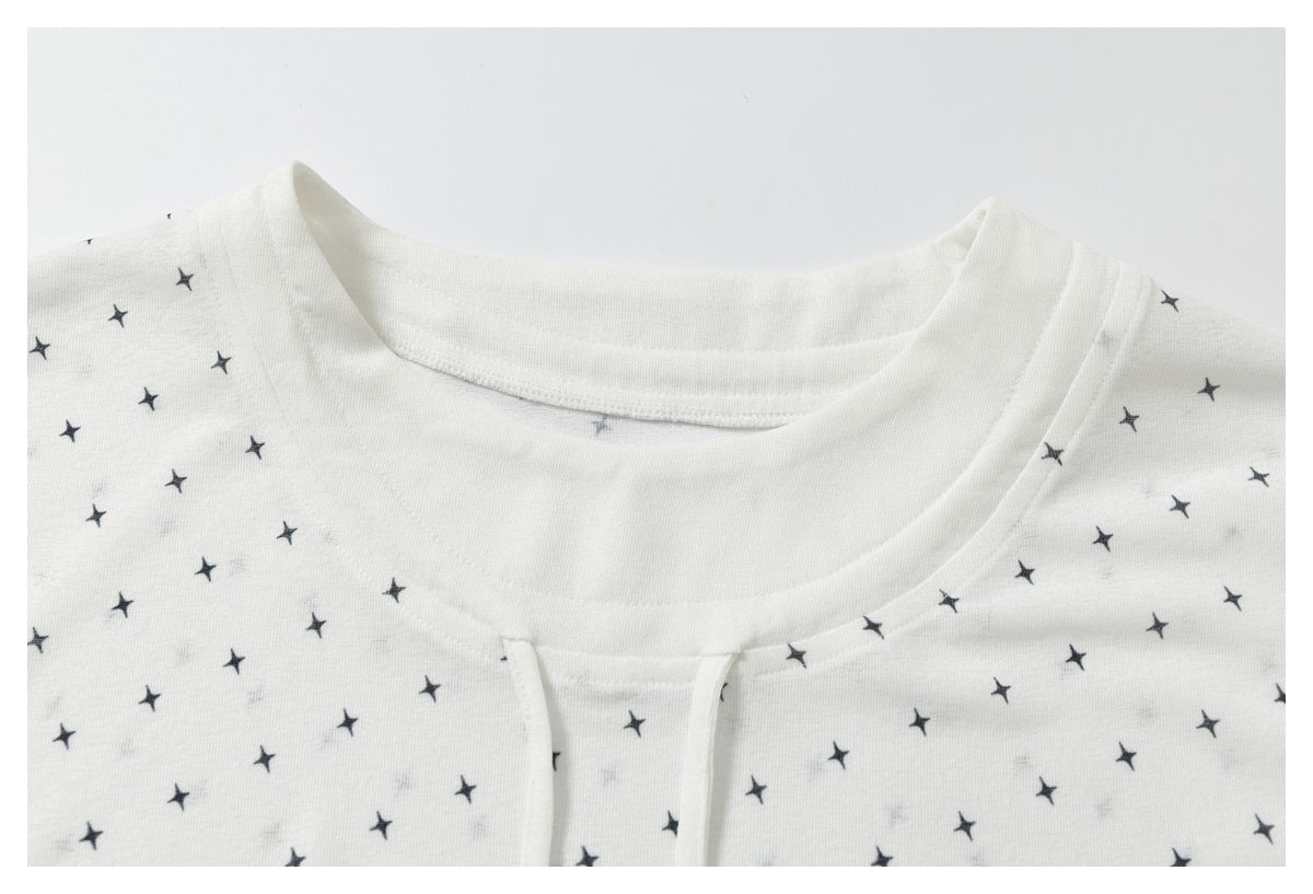 Upper-front close-up of a white star-print top with a round neckline and narrow front opening.