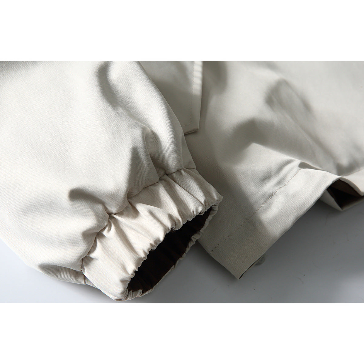 Close-up of an ivory jacket's gathered elastic cuff and sleeve seam.
