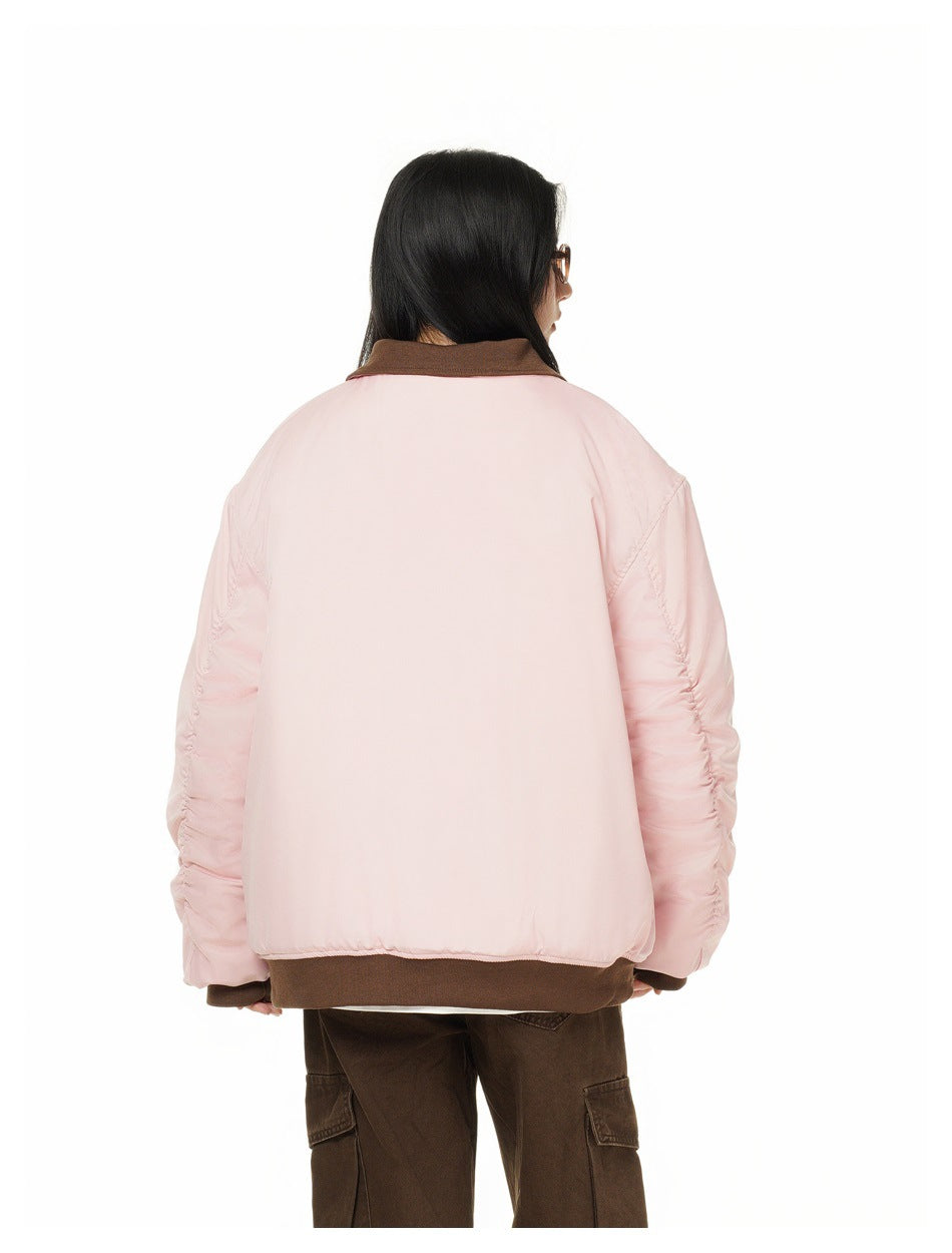 Rear view of a model wearing a pale pink jacket with a brown collar, cuffs, and hem.