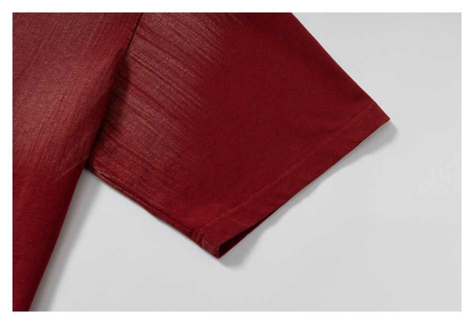 Close-up of the short sleeve and stitched hem of a burgundy T-shirt.