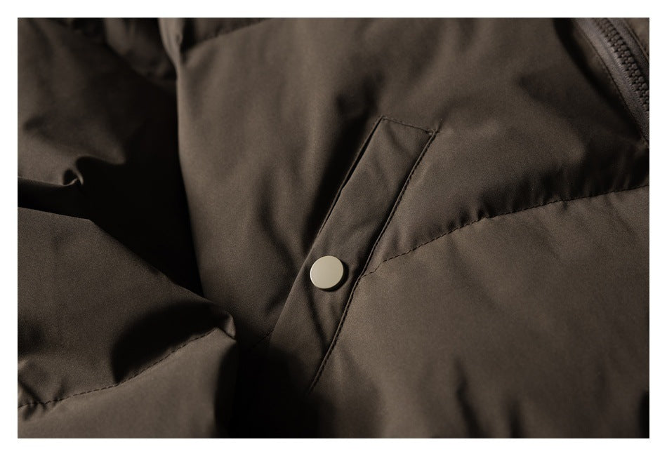 Close-up of a slanted pocket flap and round snap on the dark brown jacket.