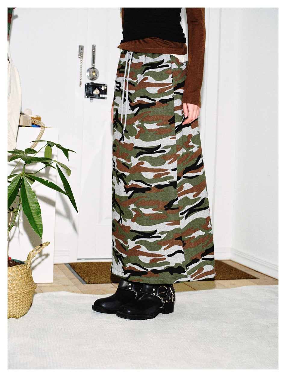 Cropped model wearing a long camouflage skirt, shown from the front with a drawstring waist.