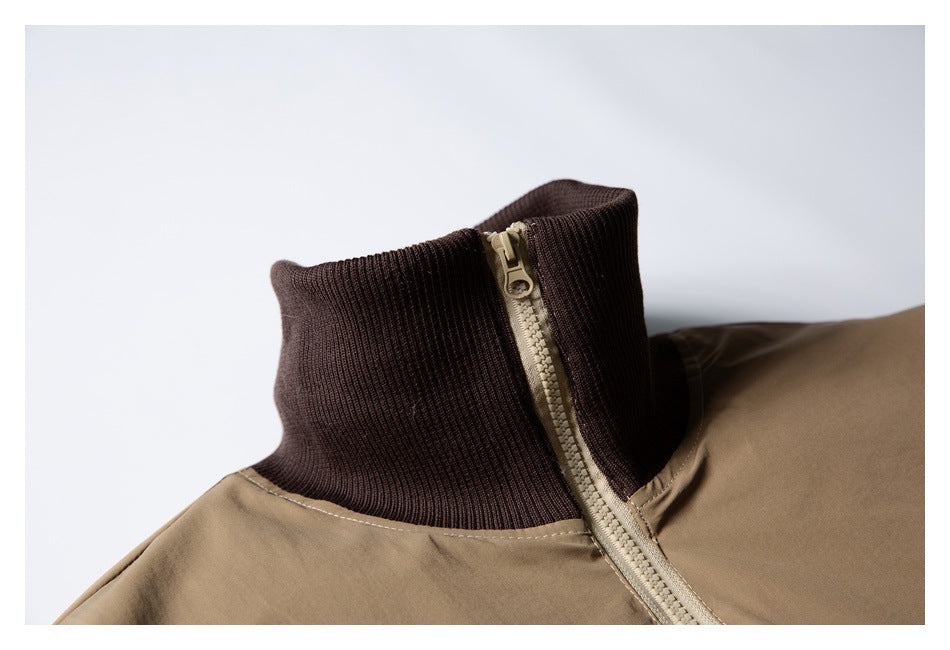 Close-up of a tan jacket’s dark brown ribbed stand collar and light-colored zipper.