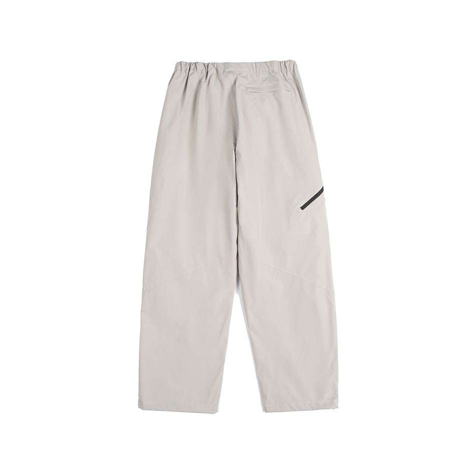 Back view of light gray loose-fit pants with an elastic waist, small rear pocket, and diagonal black leg detail.