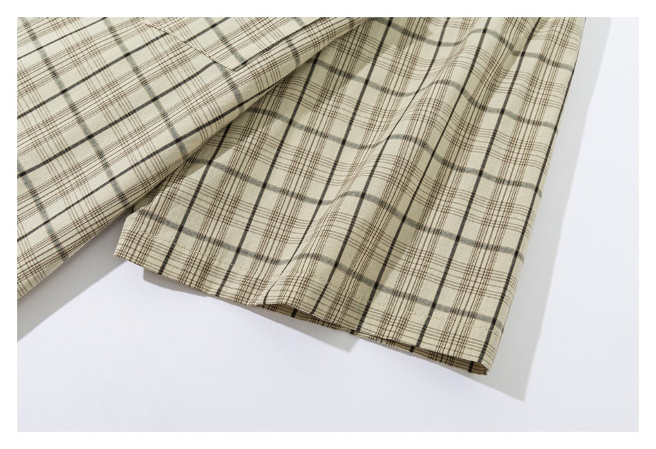 Close-up of a beige plaid shirt sleeve and stitched cuff laid flat.