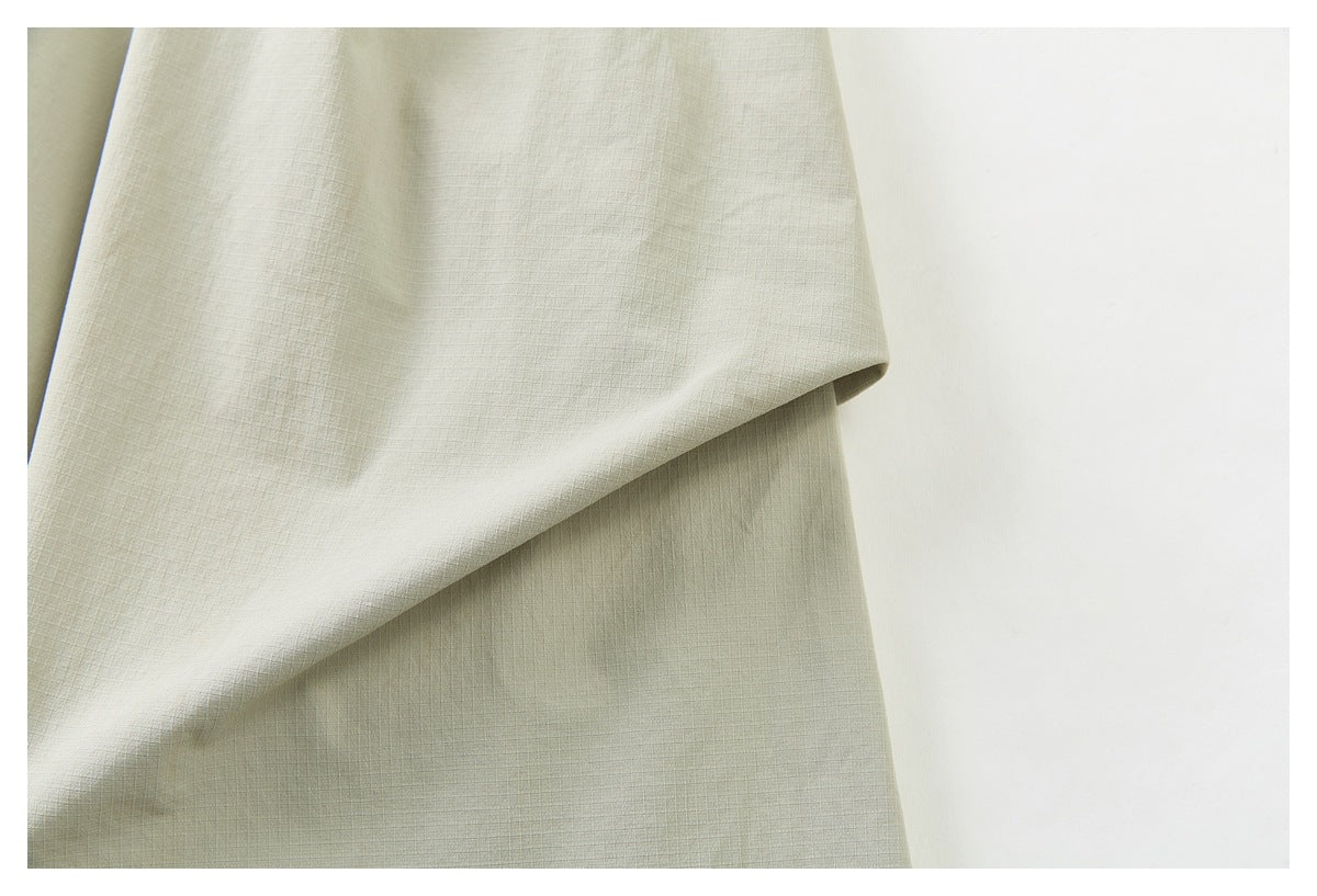 Close-up of pale khaki fabric, showing its fine crosshatch texture and a soft fold.