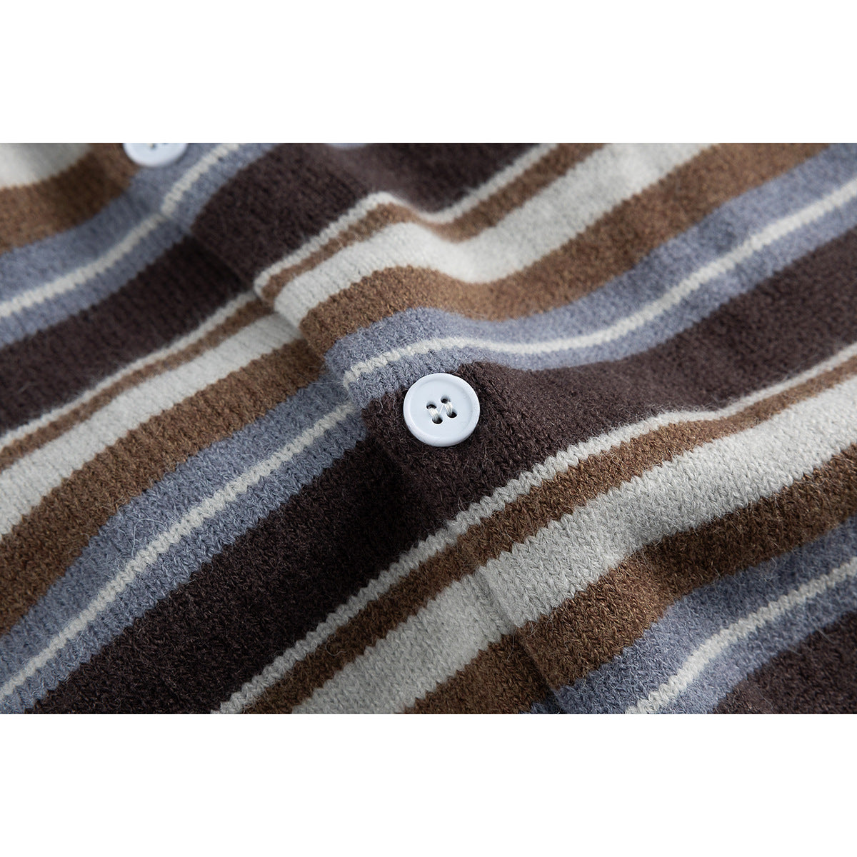 Close-up of a white button and knit stripes in brown, cream, and blue-gray on a cardigan.