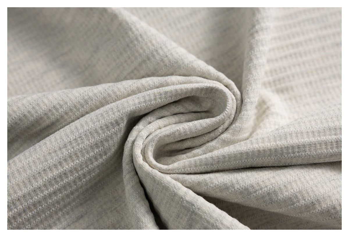 Close-up of light heather-gray knit fabric folded to show its surface and drape.