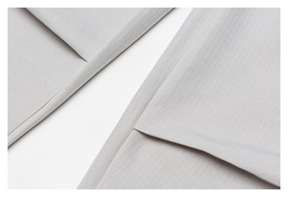Close-up of light-gray garment hems showing folded edges and clean stitching.