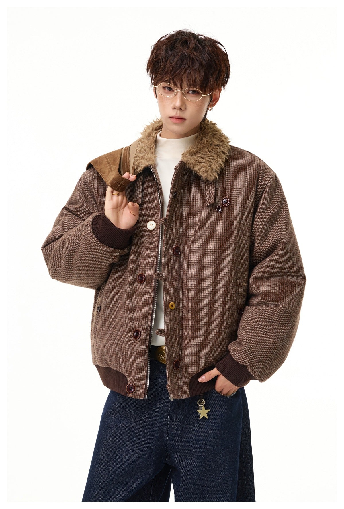 Close view of a model wearing an open brown micro-check jacket with a plush collar, front zipper, contrast buttons and ribbed