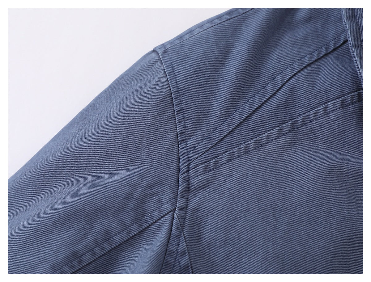 Close-up of blue-gray jacket fabric with intersecting stitched panel seams.